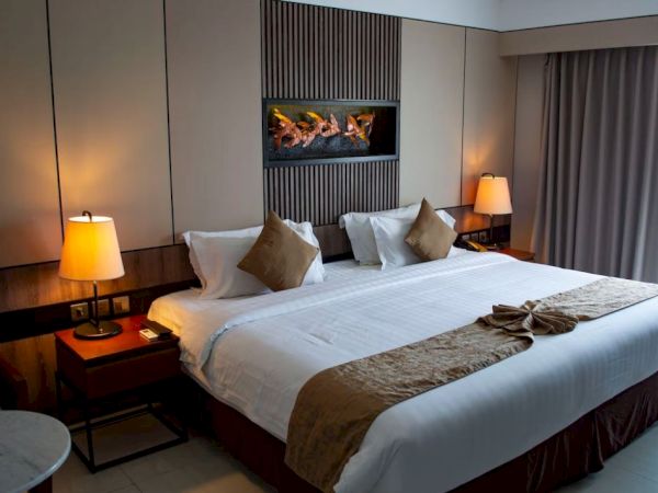 A stylish hotel room features a large bed, bedside tables with lamps, and wall decor, creating a cozy and inviting atmosphere.