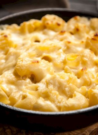 A skillet filled with creamy, baked macaroni and cheese, featuring a golden, melted cheese topping.