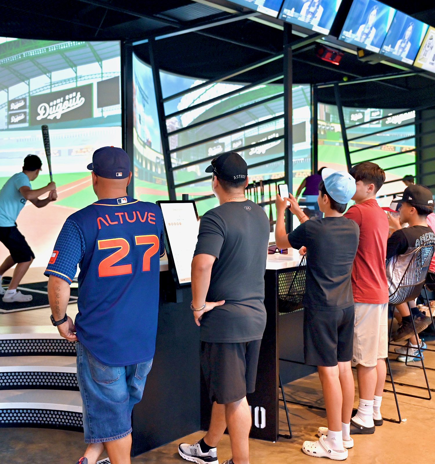 People are watching a baseball batting simulator experience.